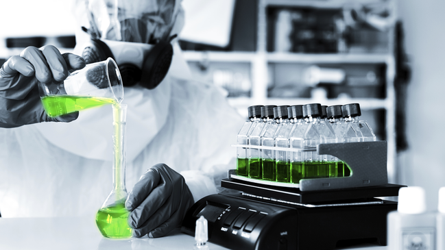 In einem Labor vermischt ein Mitarbeiter verschiedene Flüssigkeiten (verweist auf: Chemiewaffenübereinkommen)