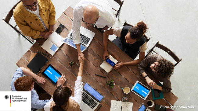 Auf dem Bild zu sehen ist, wie mehrere Personen an einem Tisch verhandeln und zwei davon sich die Hände schütteln. Auf dem Tisch liegen Arbeitsmaterialien wie zum Beispiel Laptops, Tablets und Notizbücher. Auf dem Bild zu sehen ist, wie mehrere Personen an einem Tisch verhandeln und zwei davon sich die Hände schütteln. Auf dem Tisch liegen Arbeitsmaterialien wie zum Beispiel Laptops, Tablets und Notizbücher.