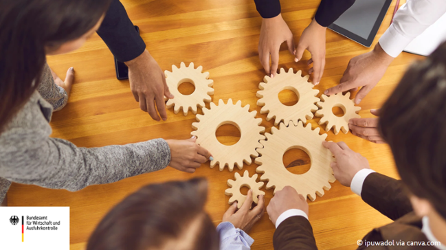 Auf dem Bild sind Personen zu sehen die hölzerne Zahnräder auf dem Tisch ineinandergreifen lassen Auf dem Bild sind Personen zu sehen die hölzerne Zahnräder auf dem Tisch ineinandergreifen lassen