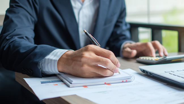 Mann sitzt am Tisch und macht sich Notizen Mann sitzt am Tisch und macht sich Notizen