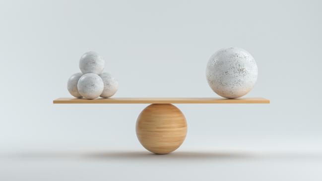 Holzwaage, die einen großen Ball und vier kleine balanciert (verweist auf: Angemessenheit und Wirksamkeit)