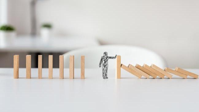 refer to: Complaints Procedure in the company Hand drawn shape of businessman stopping domino effect in a conceptual image of solving business crisis. (refer to: Complaints Procedure in the company)